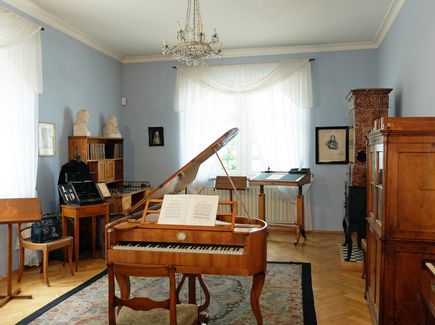 The room where Robert Schumann was born, with possessions from the Schumann-Wieck family. In the middle of the room is a grand piano and at the window a standing desk at which Schumann composed.