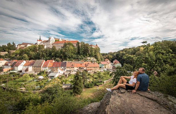 Ein Paar macht Pause bei einer Wanderung durch Bautzen. Von ihrem Felsen aus haben sie einen guten Blick auf die Ortenburg in Bautzen. 